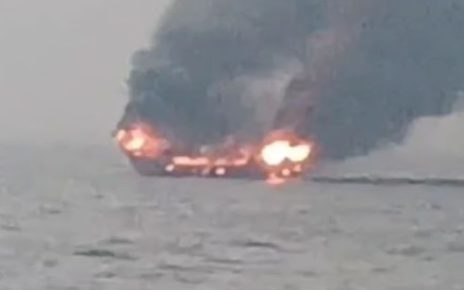 A fishing boat near Alibaug engulfed in flames, with smoke rising from the vessel as it burns on the sea.